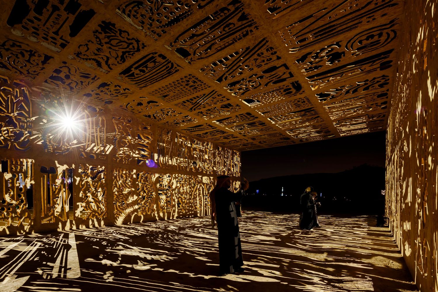 Light patterns cast through decorative ceiling create dramatic shadows in dark space.