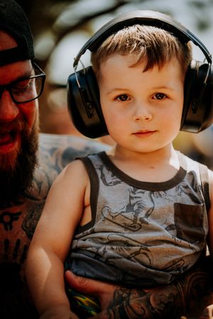 Young concertgoer wearing protective headphones at outdoor music event.