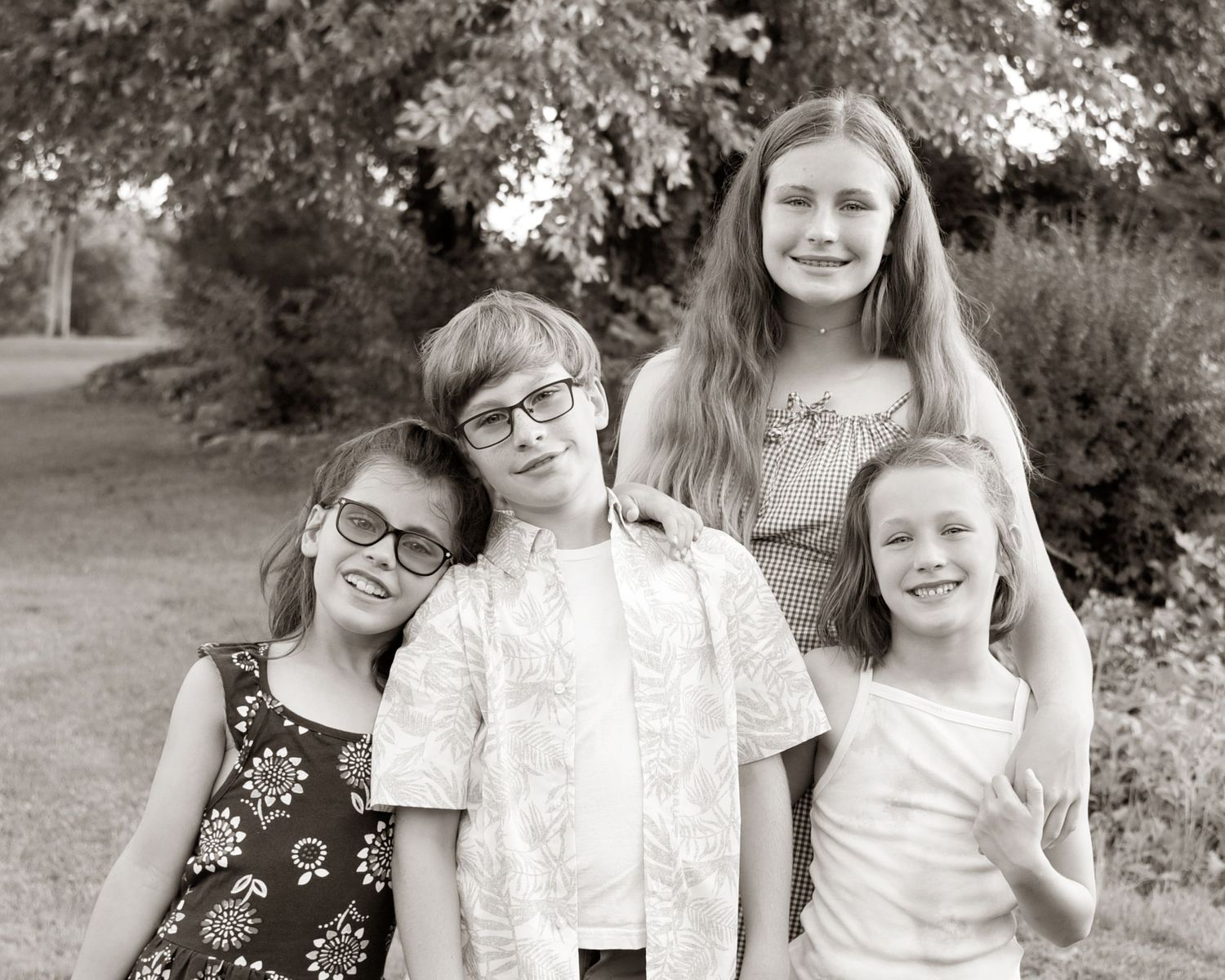 Black and white portrait of four children standing together outdoors.