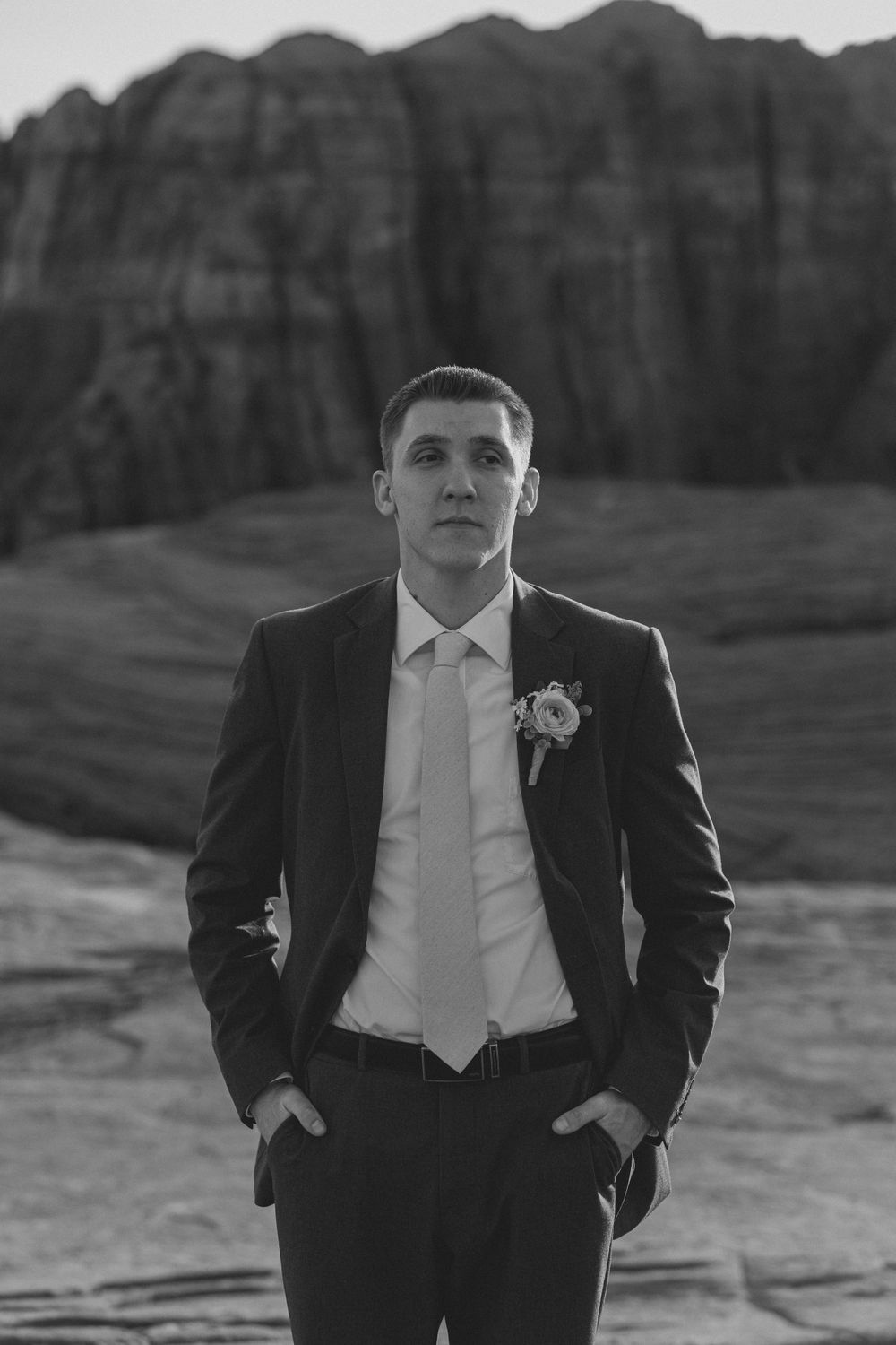 A formal portrait against dramatic red rock cliffs in black and white.