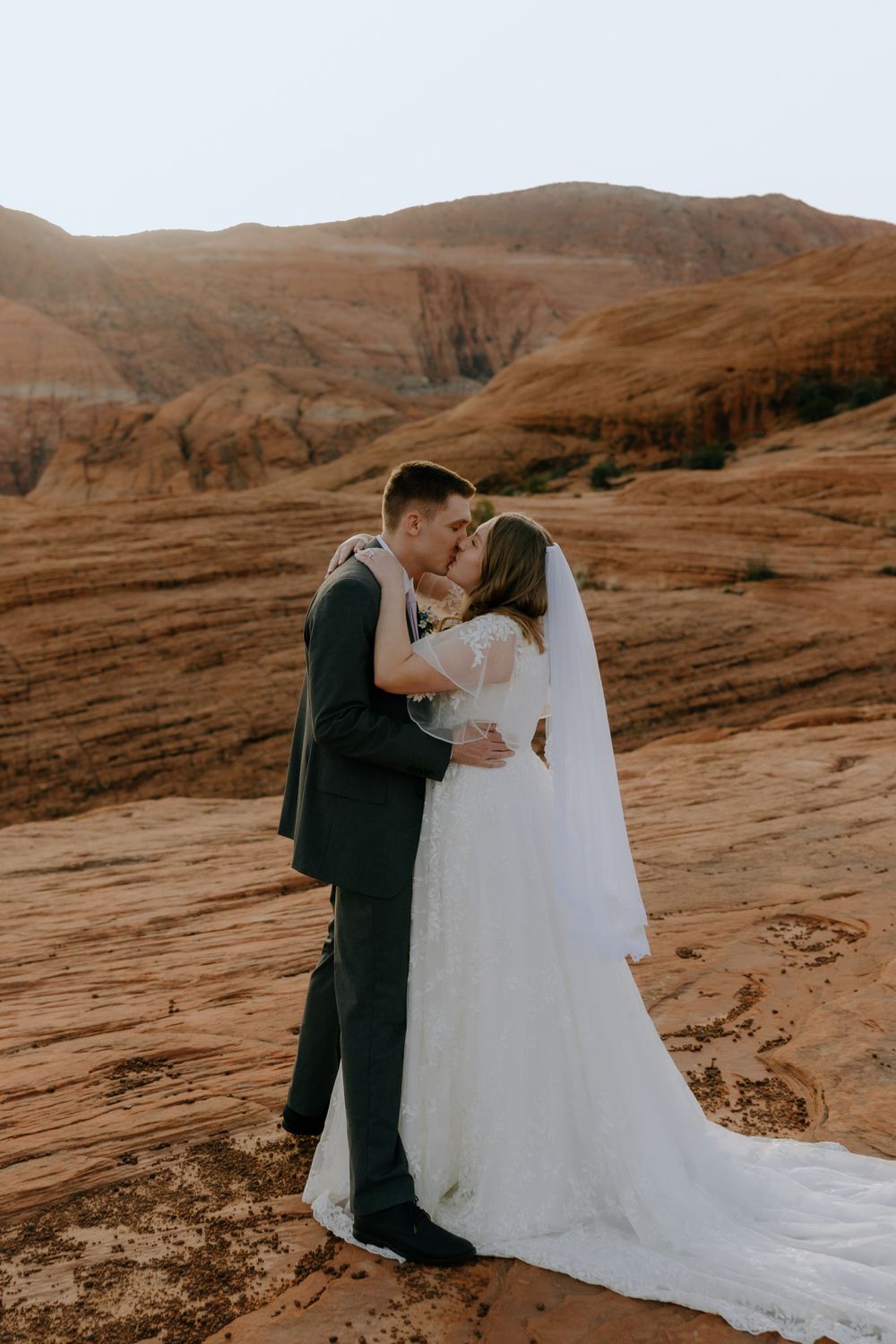 A romantic wedding portrait captured against stunning red rock formations in the desert landscape.