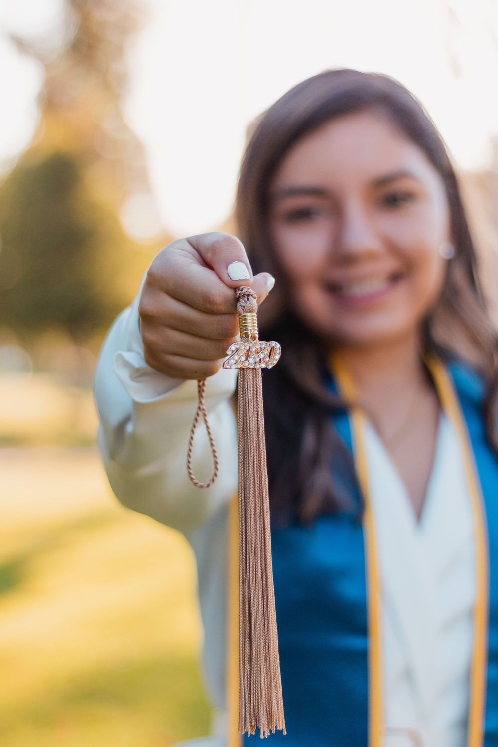 Outdoor graduation portrait of a college senior with close-up detail shot of tassel in Fresno, California