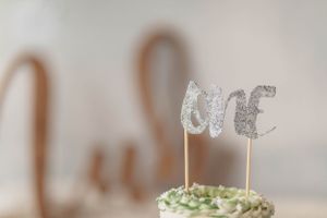 Close-up of a silver glitter 'ONE' cake topper decoration.