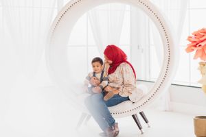 Two people share a playful moment while sitting in a decorative round mirror frame.