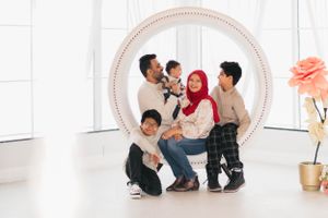 A family group poses together inside a large white circular frame in a bright studio setting.