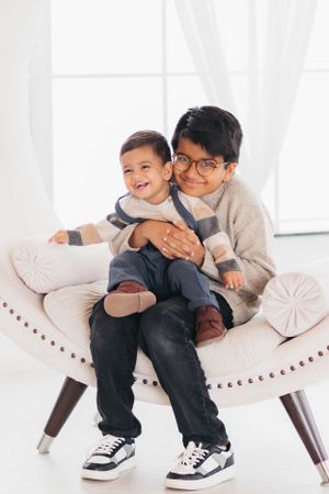 Two people share a warm embrace while sitting on a modern white accent chair.