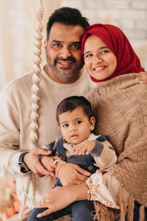 A heartwarming family portrait with neutral tones and a decorative rope swing element.
