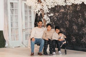 Family photo session in front of vintage doors and dark textured backdrop.