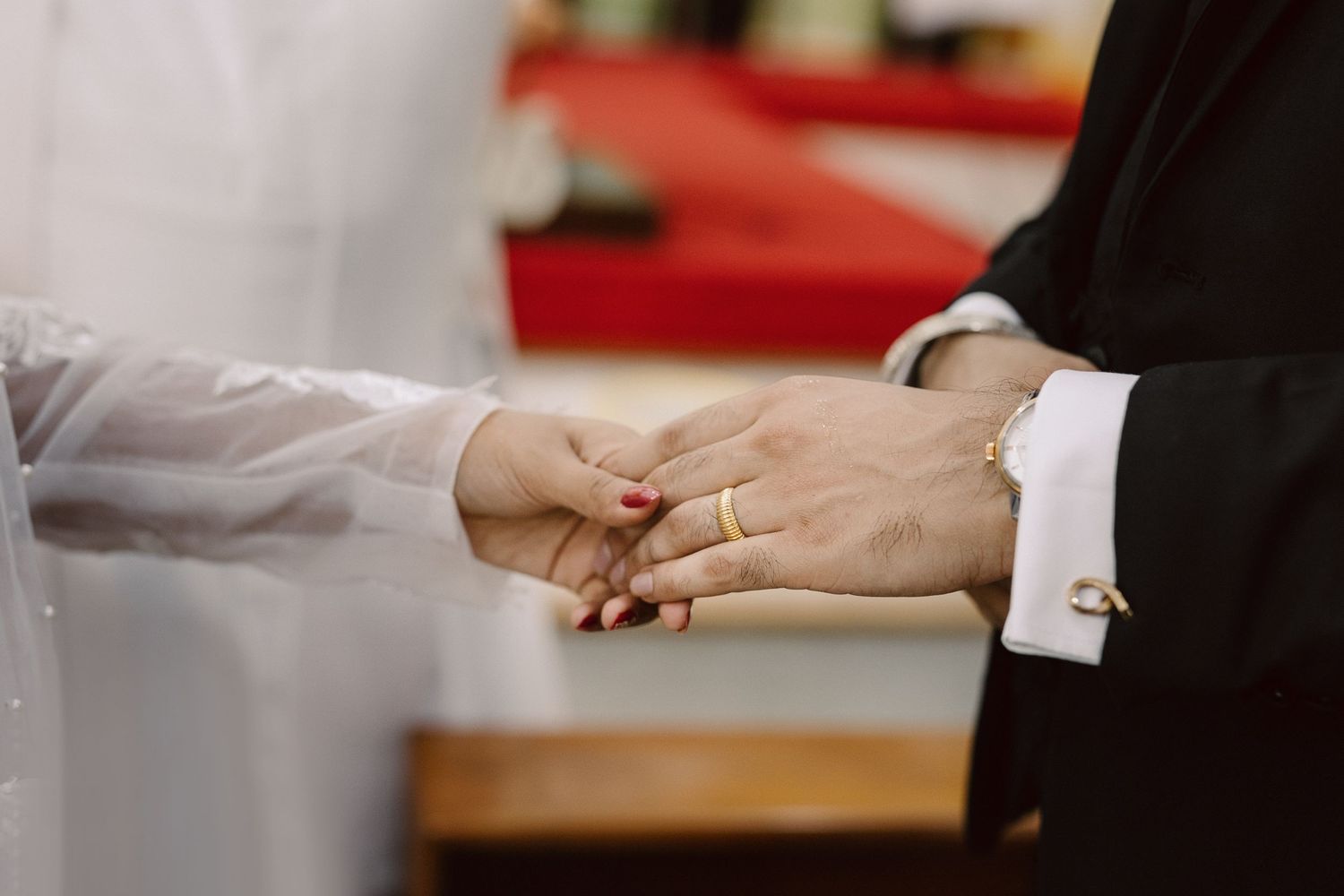 Close-up shot of hands during a wedding ring exchange ceremony.