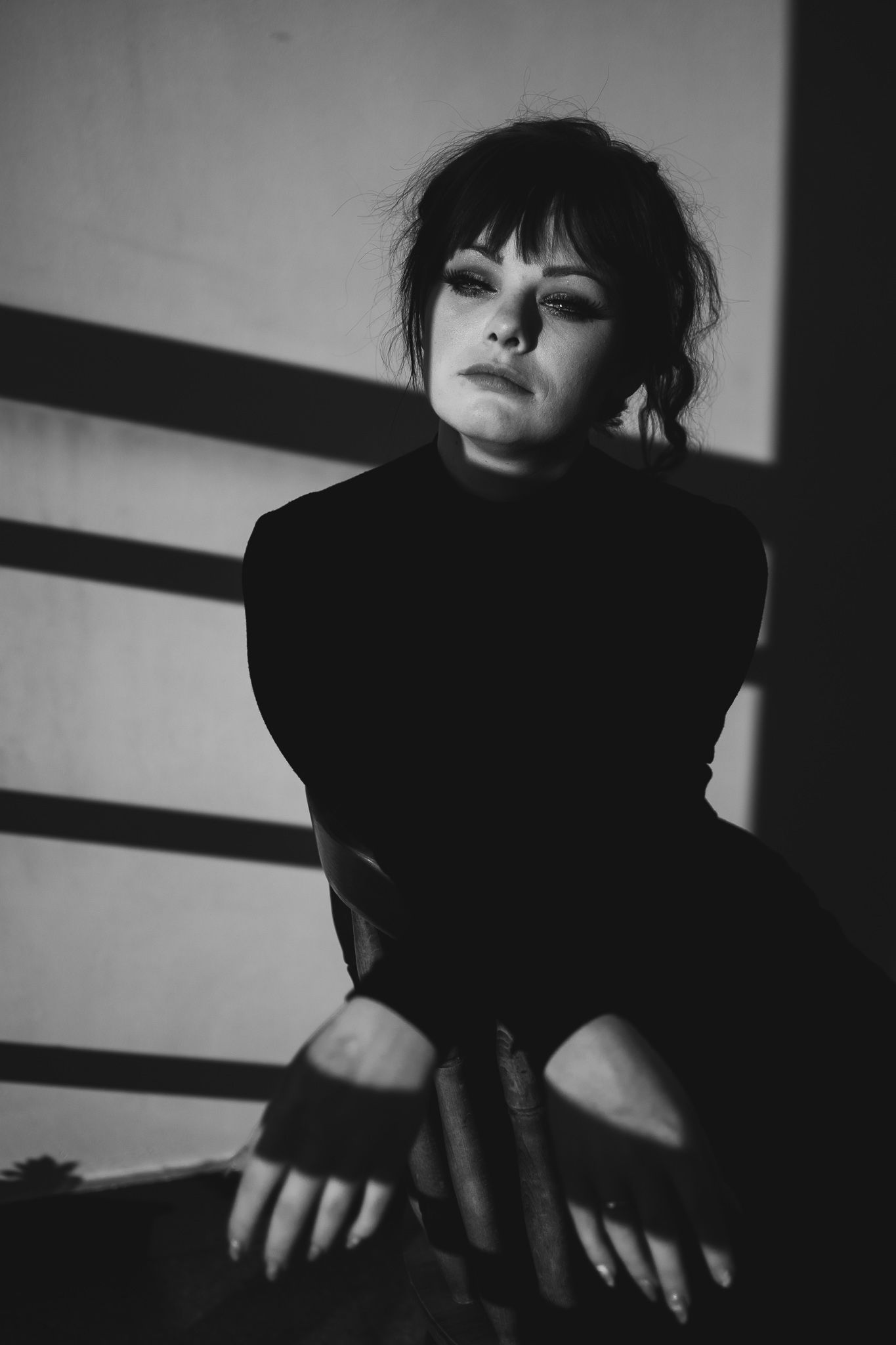 Dramatic black and white portrait with moody lighting and dark fashion styling.