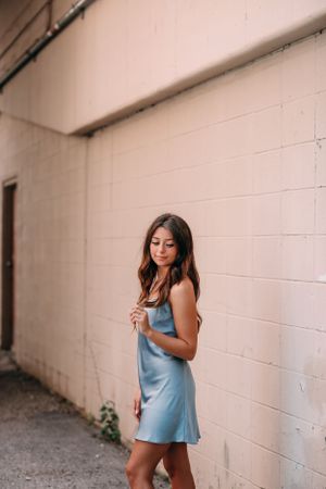 girl wearing blue dress in front of plain wall