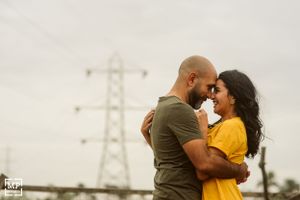 A couple embracing outdoors with power transmission towers visible in the background.