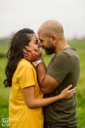 A romantic couple shares an intimate moment in a field, with one wearing yellow and the other in olive green.