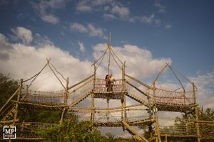 A wooden scaffolding structure stands against a blue sky with fluffy clouds.