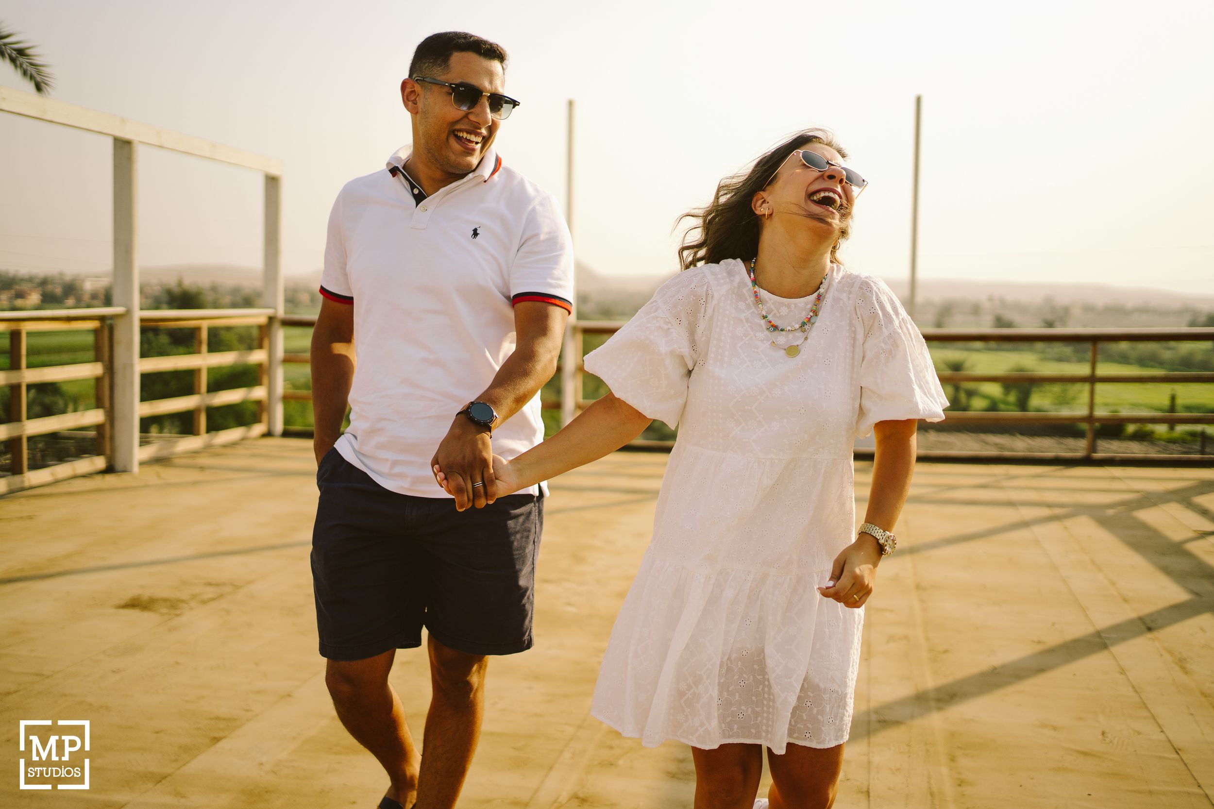 A couple laughs together on a rooftop during golden hour.