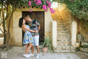 Romantic moment between couple near stone wall with pink bougainvillea flowers.