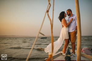 A couple shares a romantic moment on a wooden dock at sunset.