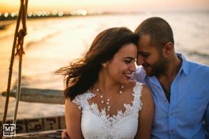 Intimate sunset moment between couple wearing white dress and blue shirt.