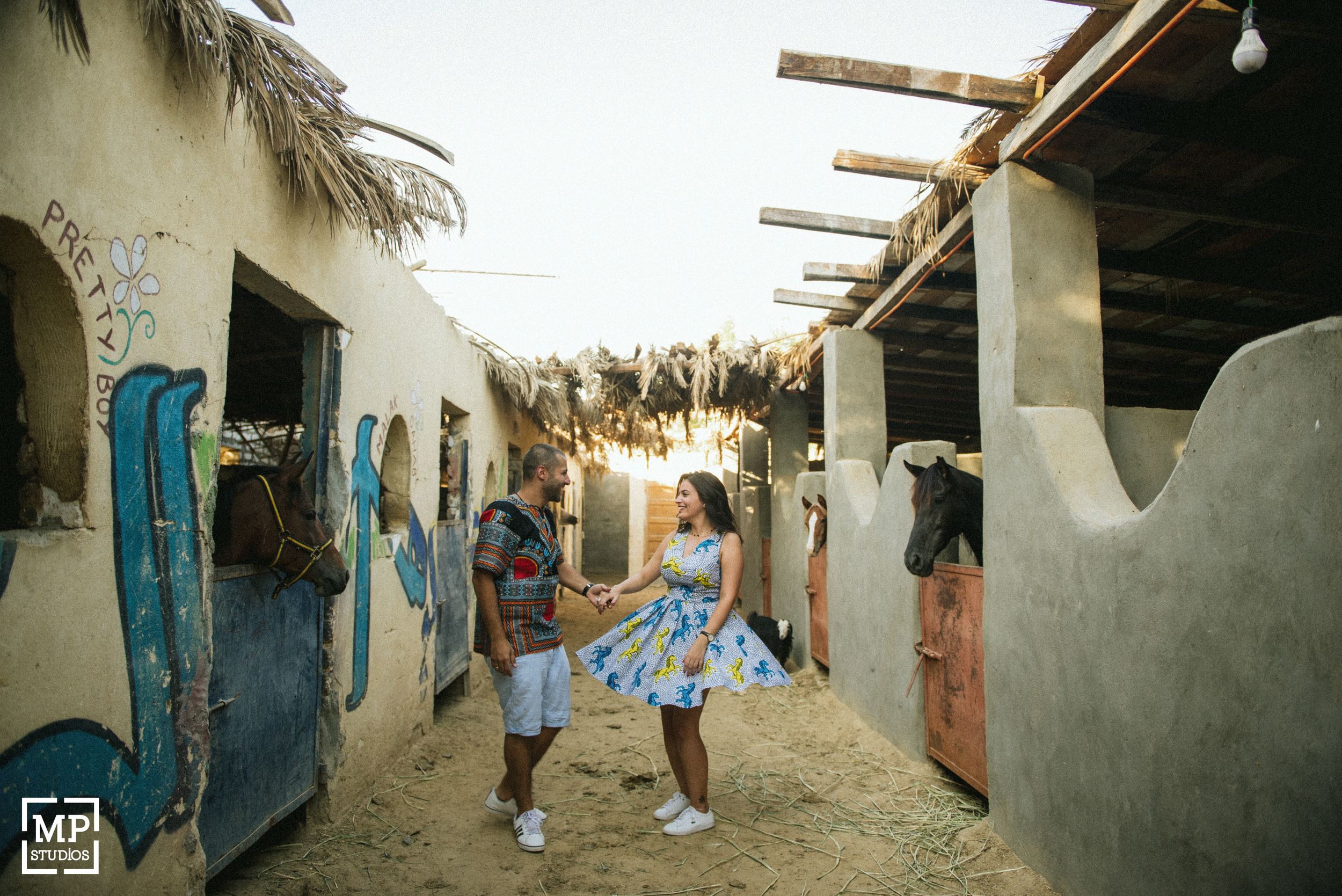 Couple playing in rustic alley with white walls and blue doors in summer setting.