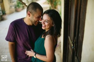 A couple shares an intimate laughing moment on a porch.