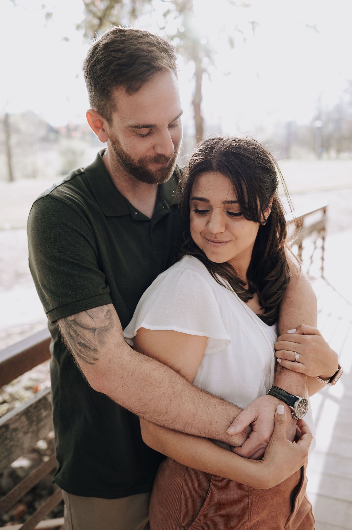 A couple embraces tenderly on a wooden deck during an outdoor photoshoot.