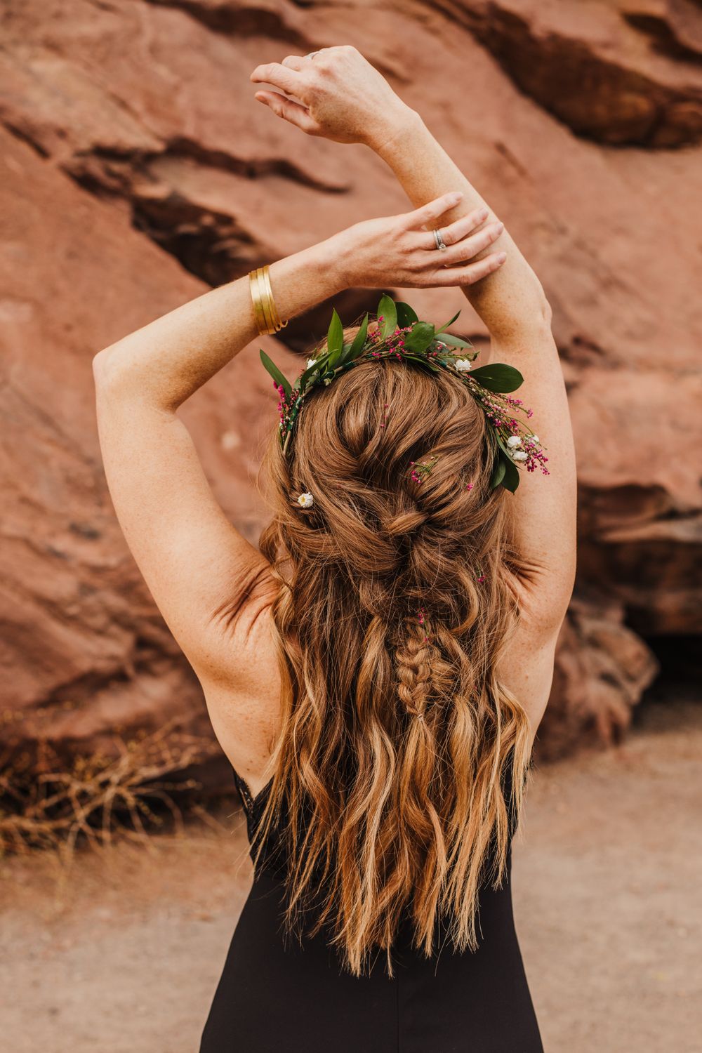 Person with floral hair accessories poses against red rock canyon wall.