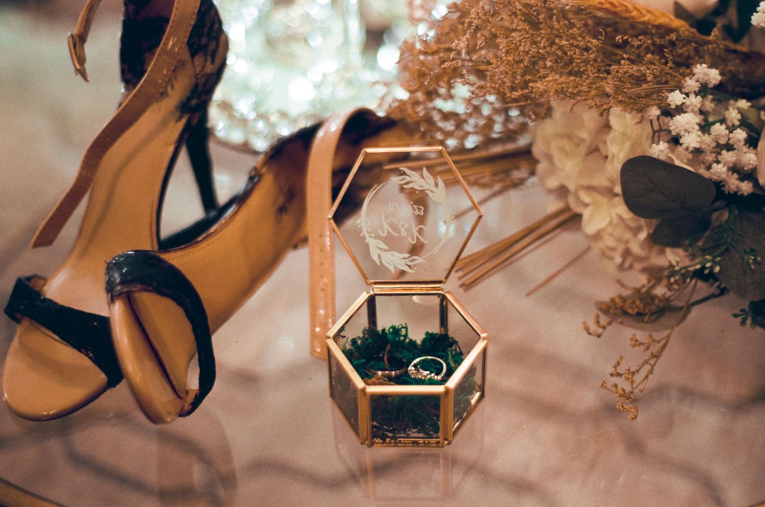 Wedding accessories including gold heels and a hexagonal jewelry box with dried flowers.