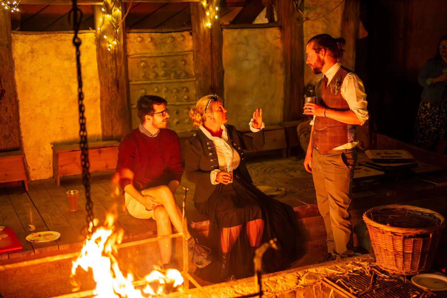 Festive outdoor gathering with people celebrating around a bonfire at night.