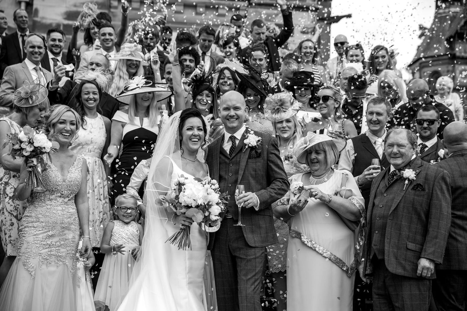 Wedding guests throwing confetti over Bride & Groom
