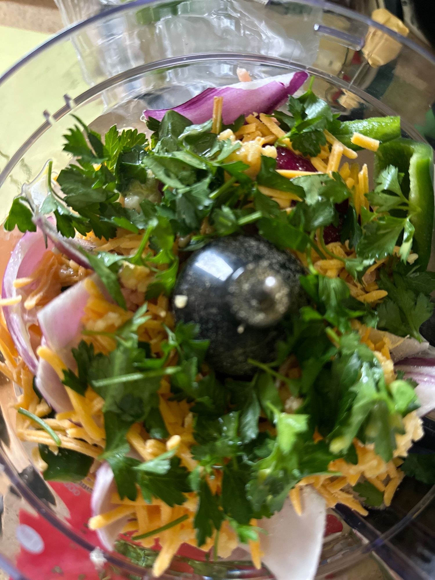 Fresh cilantro, grated cheese, and red onions mixed in a food processor bowl.