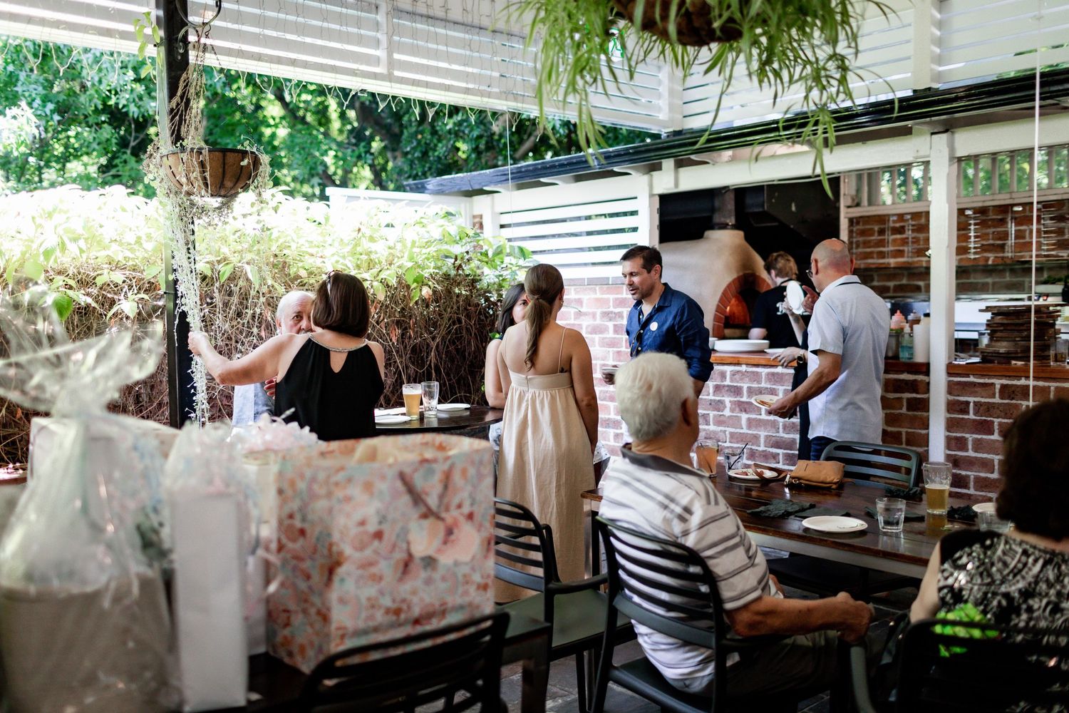 Guests gathering at an outdoor baby shower celebration under a covered patio.