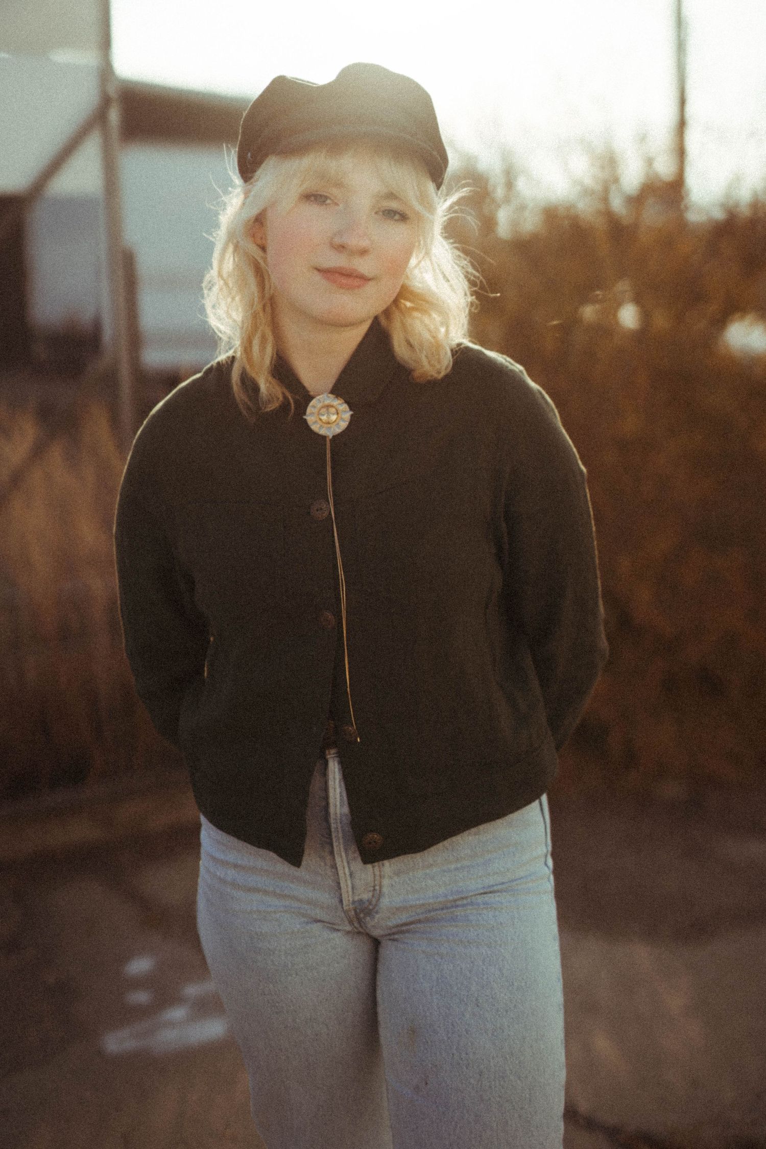 Vintage-style portrait in golden hour light featuring casual denim and baseball cap fashion.