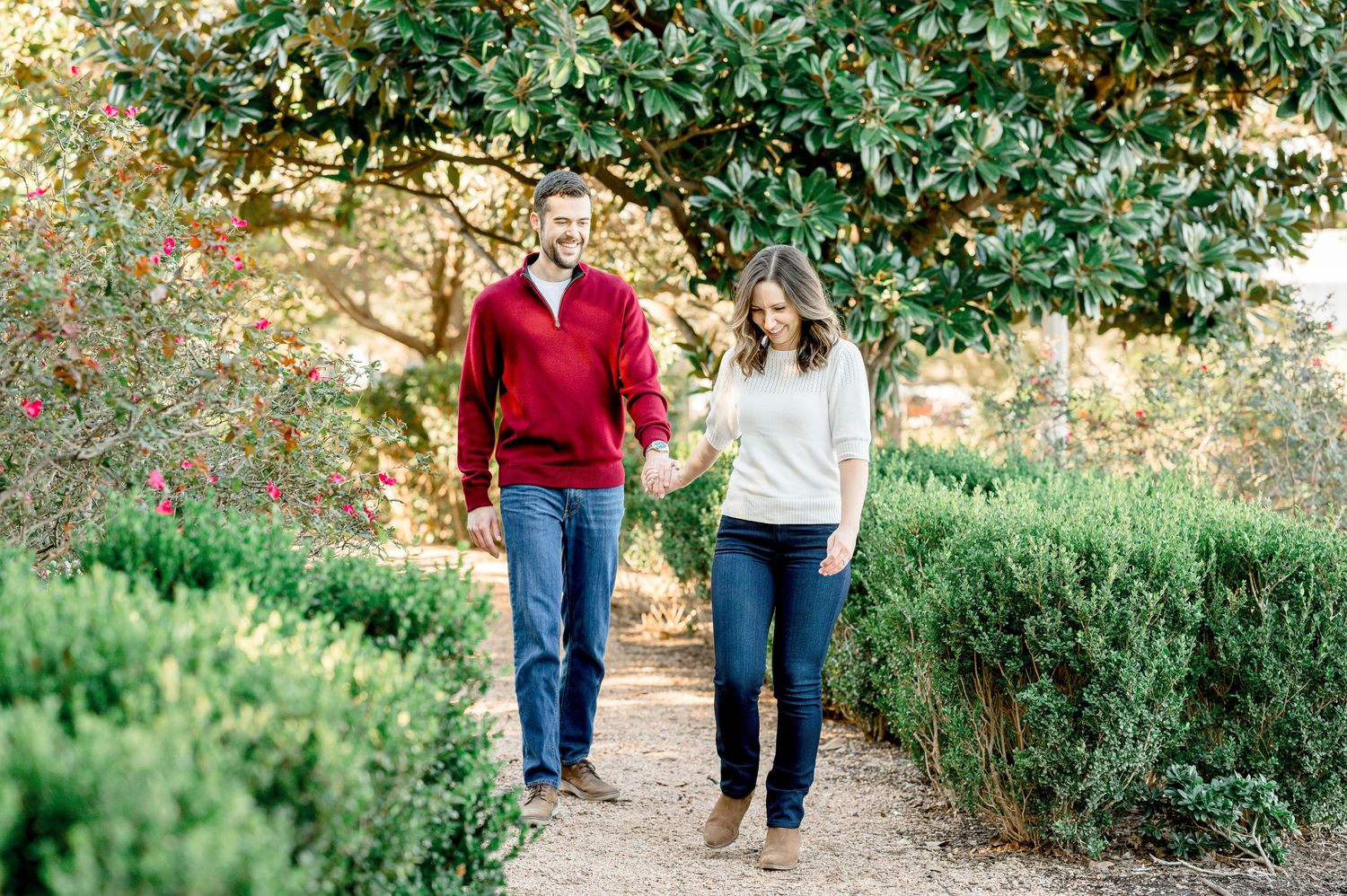 A couple walks together on a garden path surrounded by lush greenery.