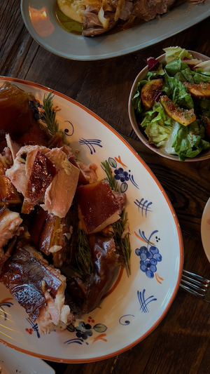 Tender roasted meat dish served with fresh salad on a traditional floral-patterned plate.