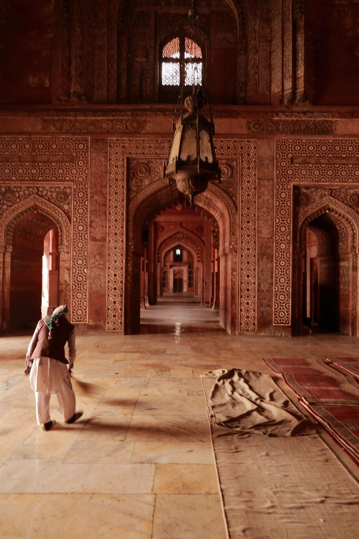Detailed interior corridor of a Mughal palace showing intricate carved archways and decorative stonework.