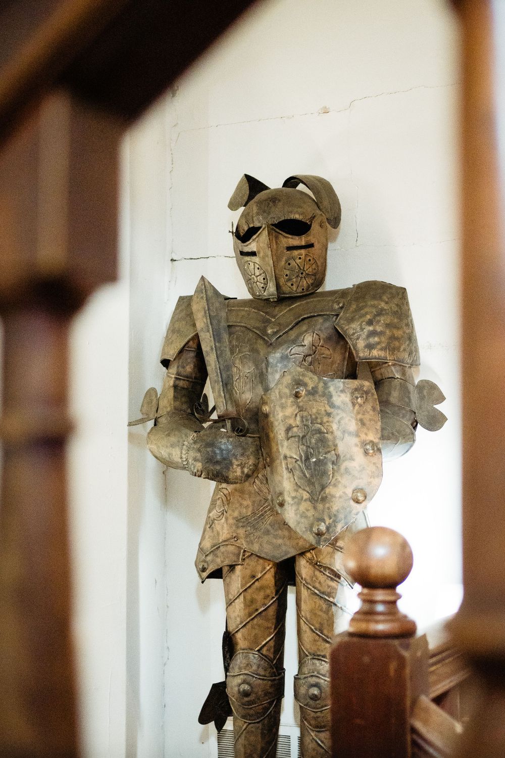 Vintage decorative suit of armor statue on display against white wall.