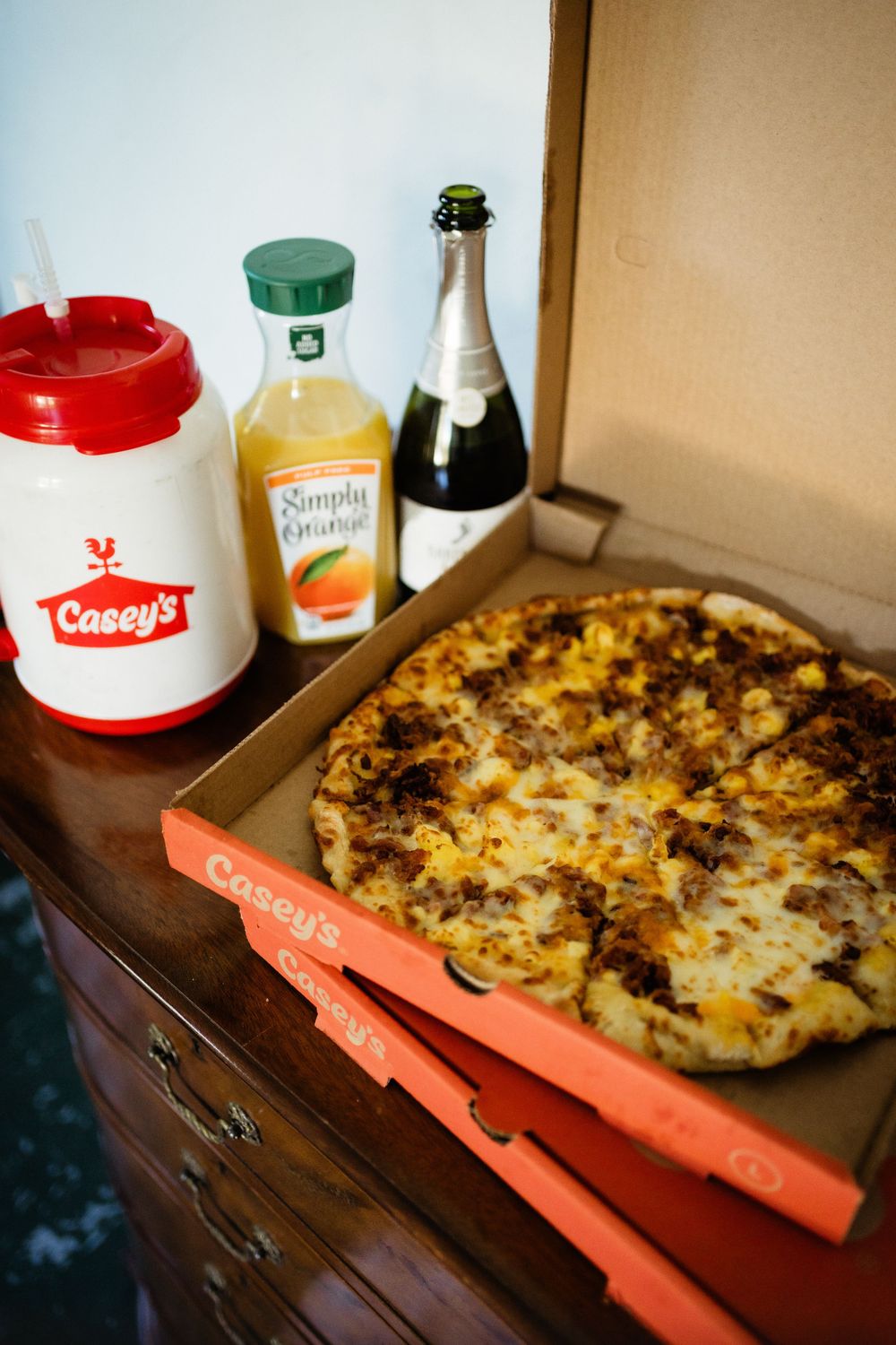 A Casey's pizza box with drinks and beverages displayed on a wooden surface.