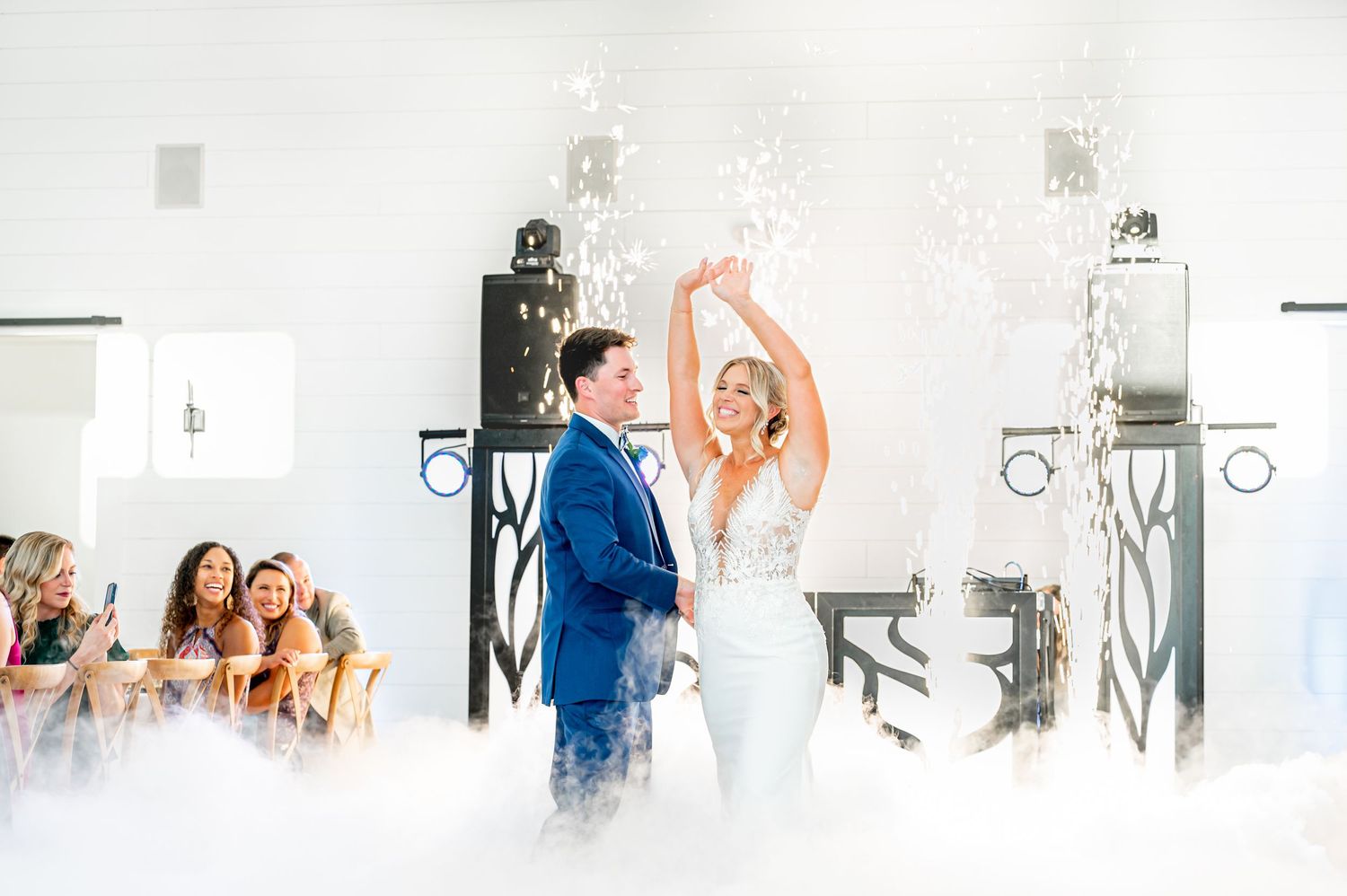 Wedding couple dancing in fog with dramatic lighting on white dance floor.