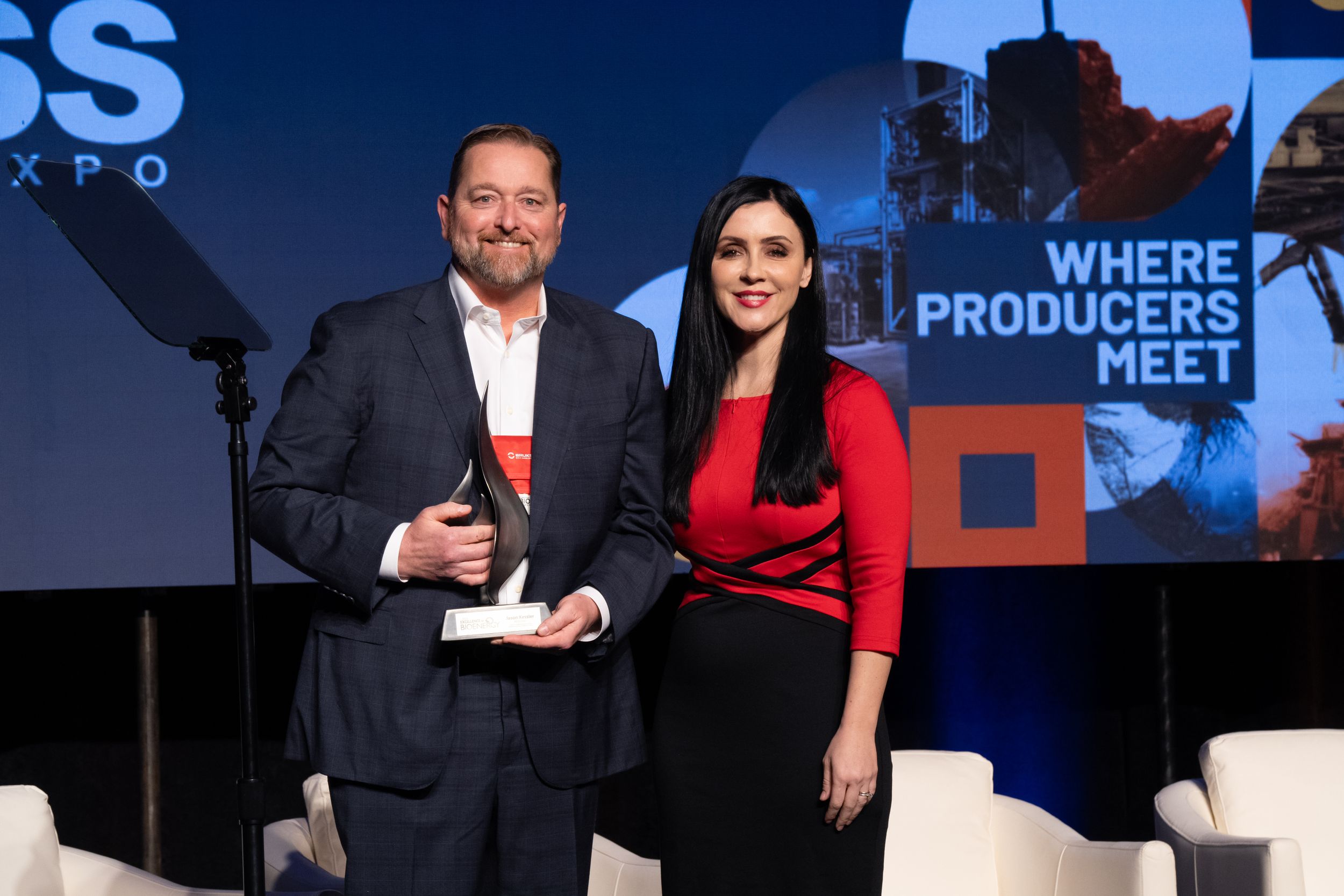 Two professionals on stage during an award ceremony, celebrating achievements and networking at BIOMASS event