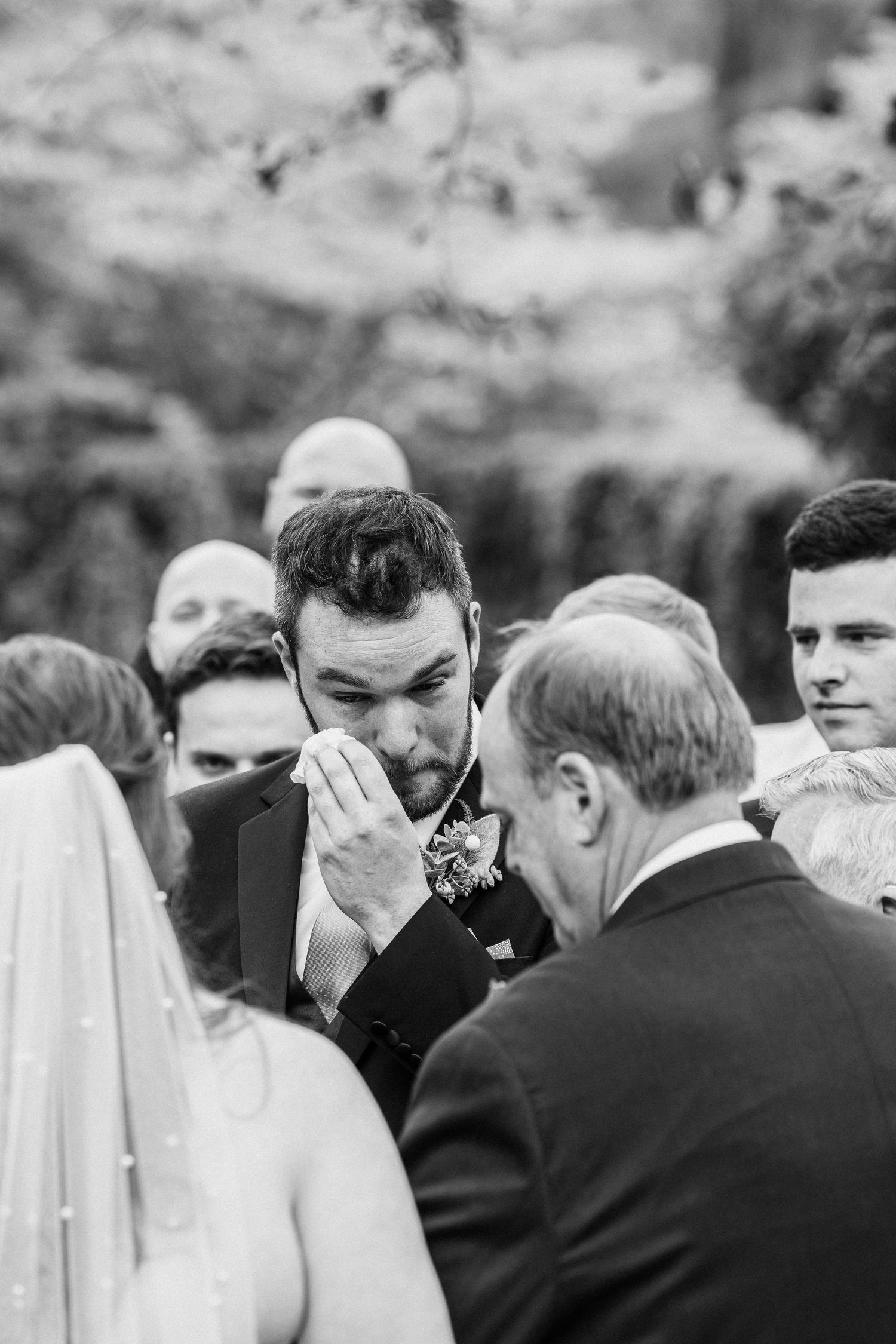 Groom drying tears as the father of the bride gives his daughter away at the wedding.