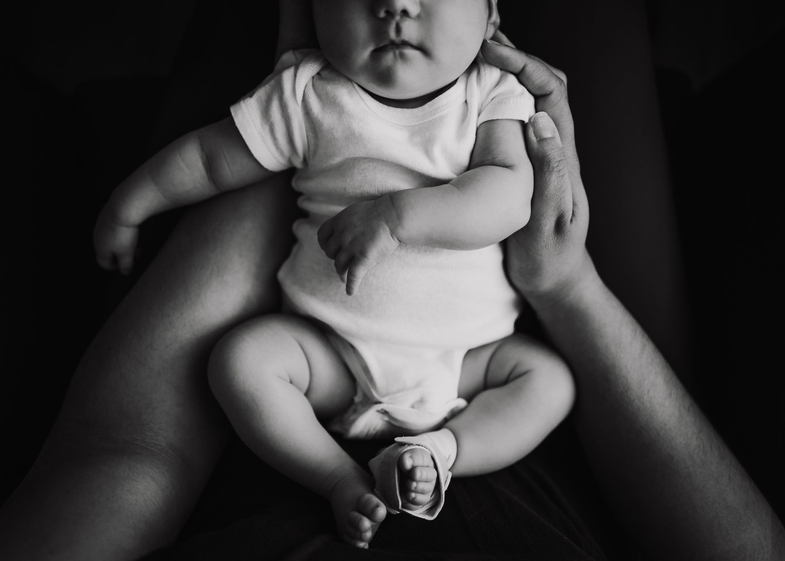 Black and white overhead view of infant wearing white onesie.