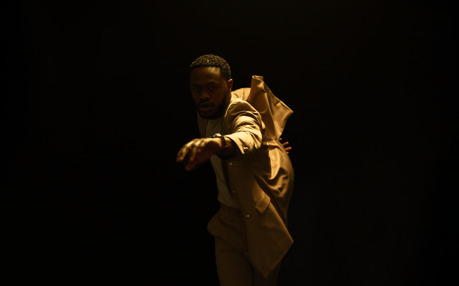 Dramatic silhouette of performer making dynamic pose against dark background.