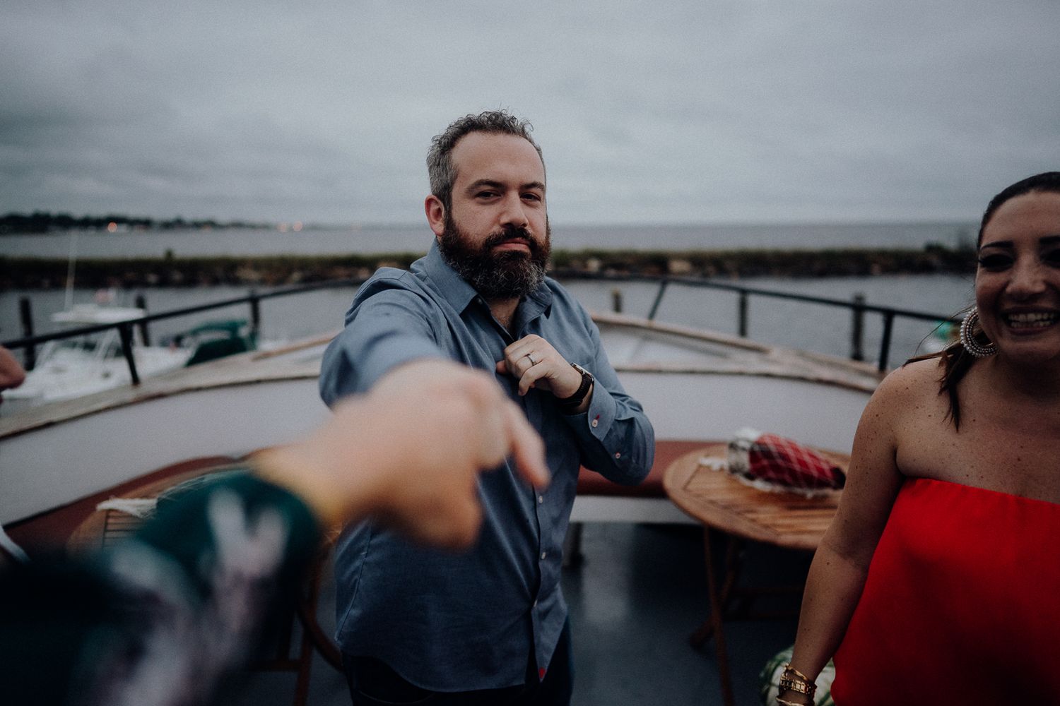People enjoying drinks and conversation on a boat deck under cloudy skies.