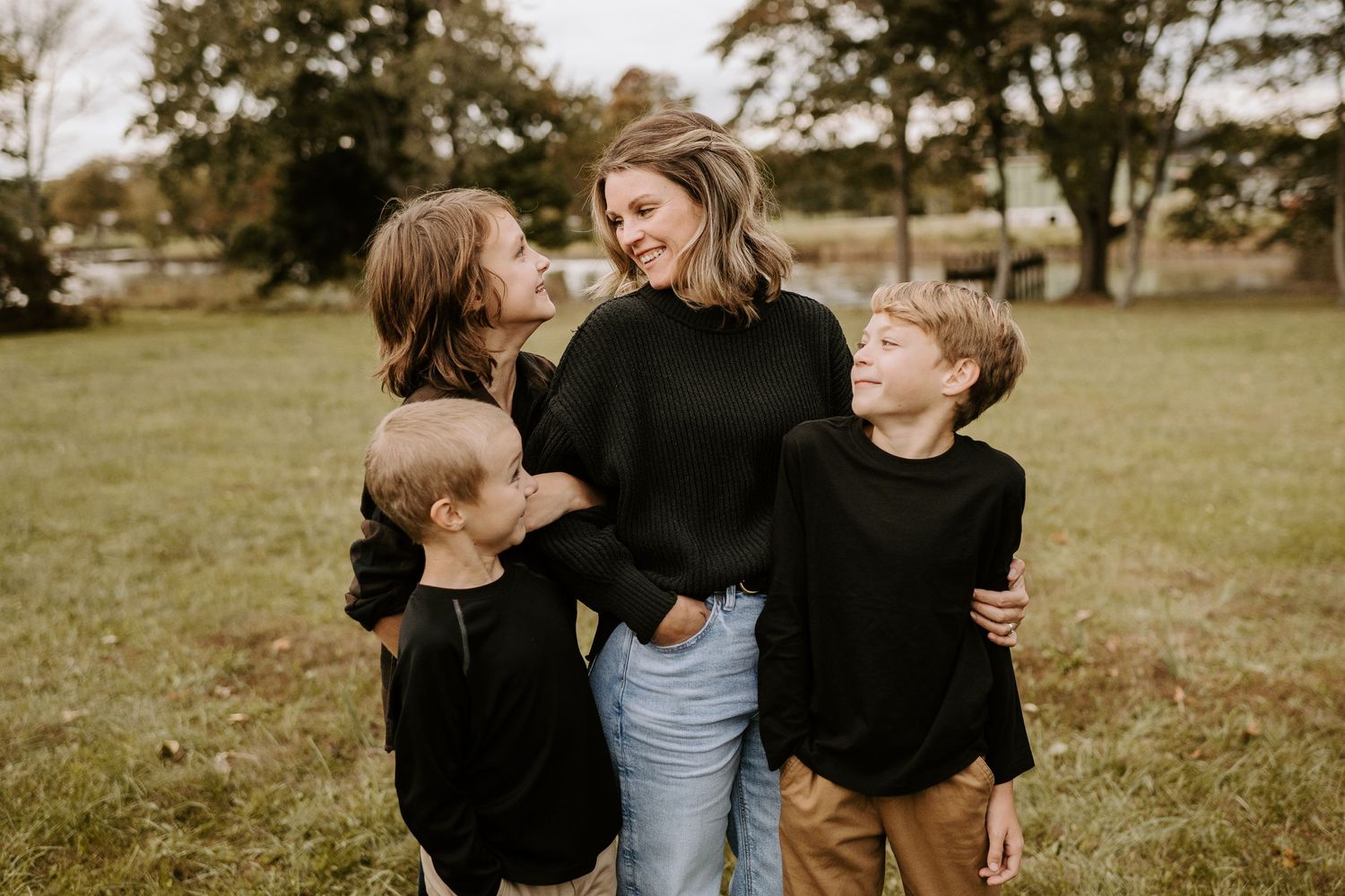 Candid family moment showing joyful laughter while posing outdoors in matching black sweaters.
