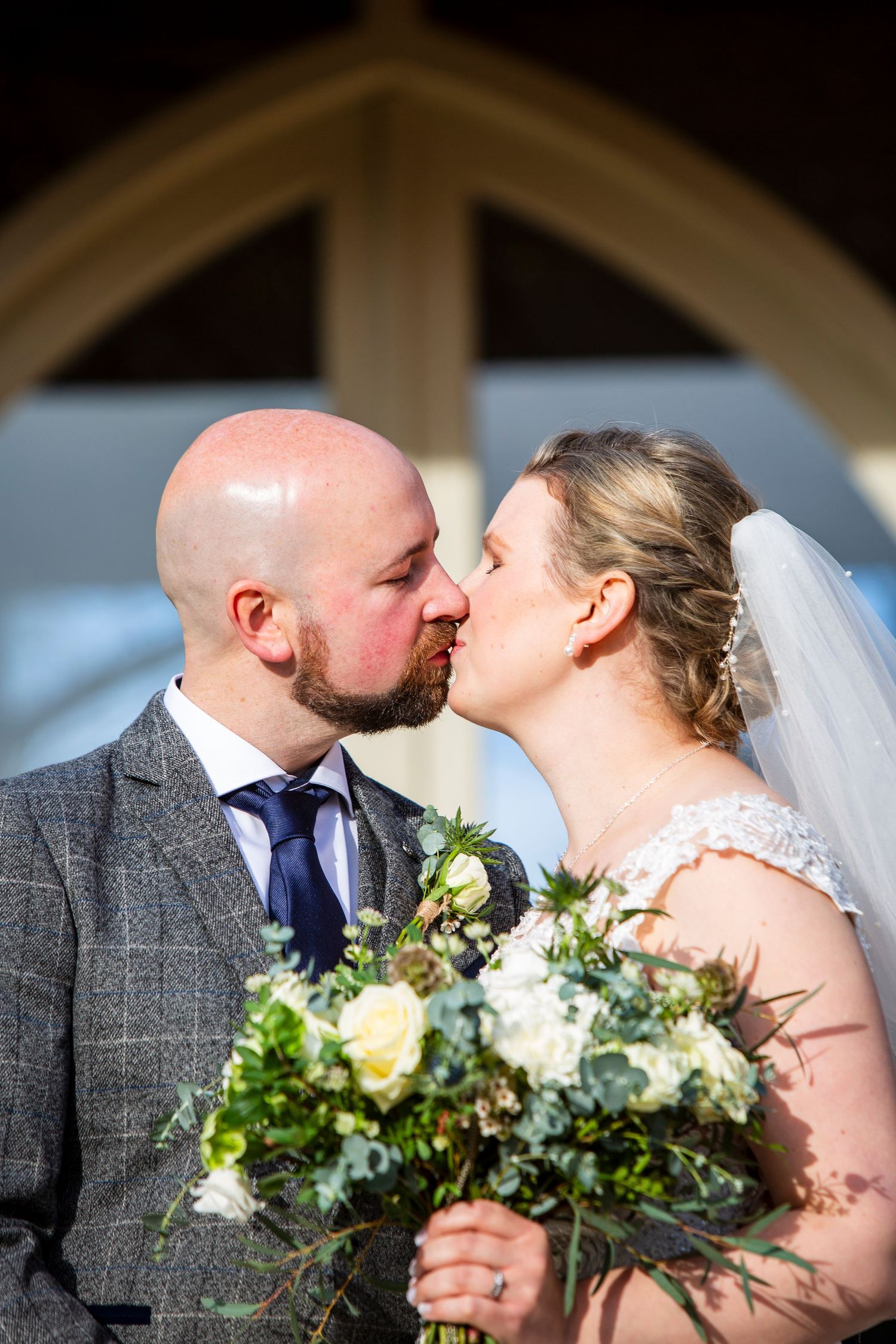 Intimate wedding portrait with elegant bouquet featuring yellow roses and greenery.