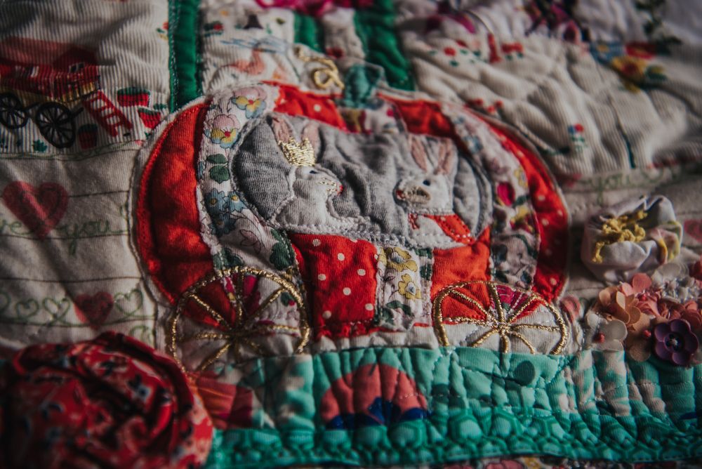 Applique of a carriage with 2 rabbits on it taken from a piece of baby clothes and put on a quilt.