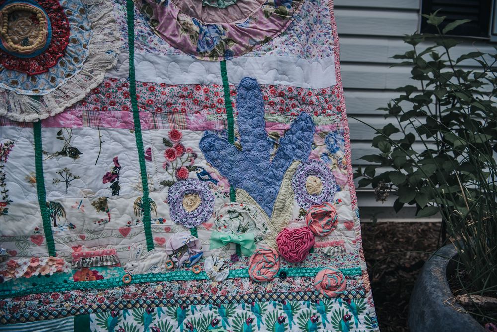 Applique of purple flowers on a large memory quilt made with clothes.