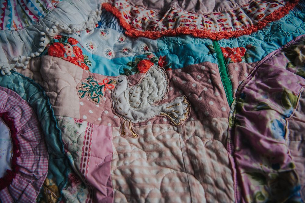 Memory quilt made with baby clothes with a dove applique on it.