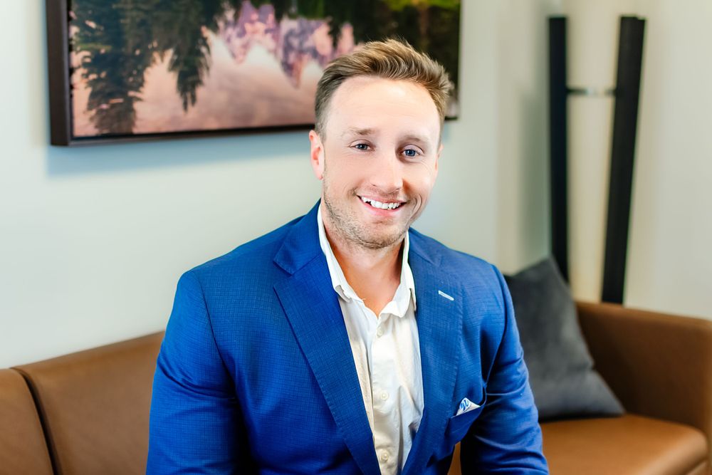Corporate portrait of businessman in blue blazer with bright smile.