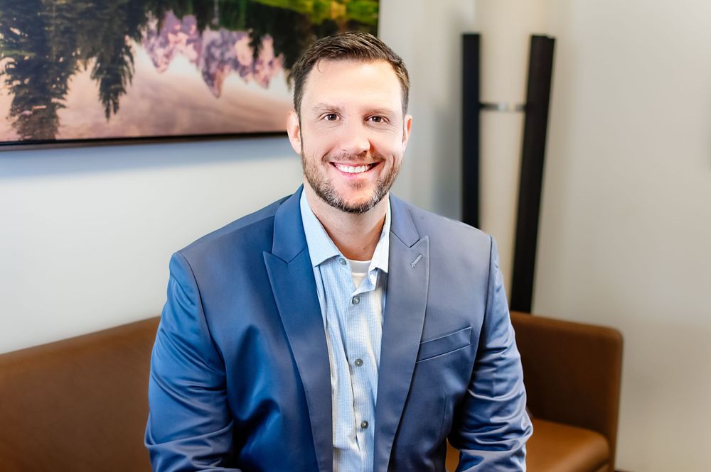 Professional headshot of smiling executive in blue suit jacket.